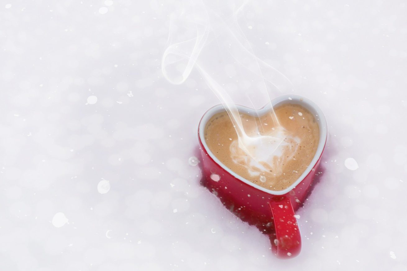 En bild på en rykande hjärtformadkopp choklad i snö. 