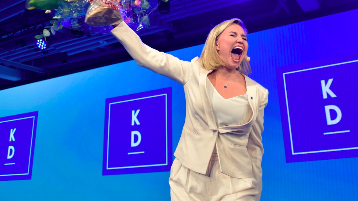 Ebba Busch Thor jublar på en scen med en blombukett i handen. 
