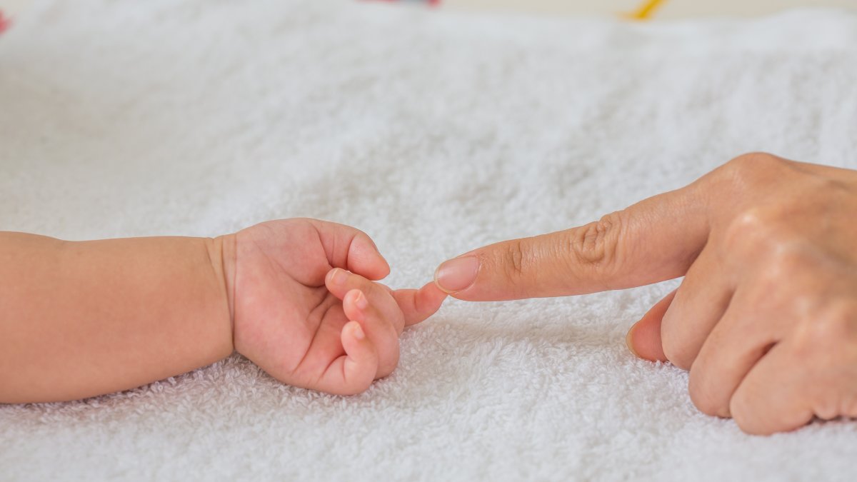 En bebishand som håller i en vuxen persons finger.