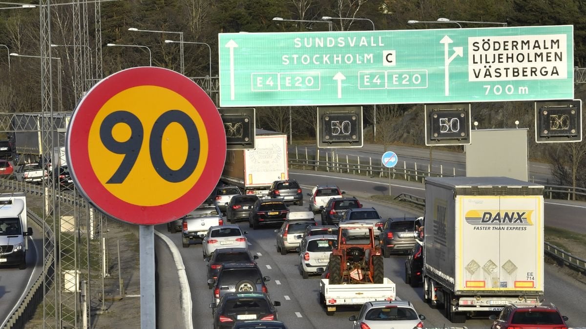 Hastighetsskylt och en motorväg med lastbilar och bilar.