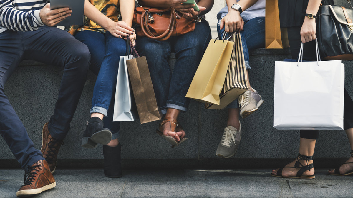 Flera människor sitter med shoppingpåsar