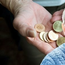 Mynt i en hand och en äldre person.
