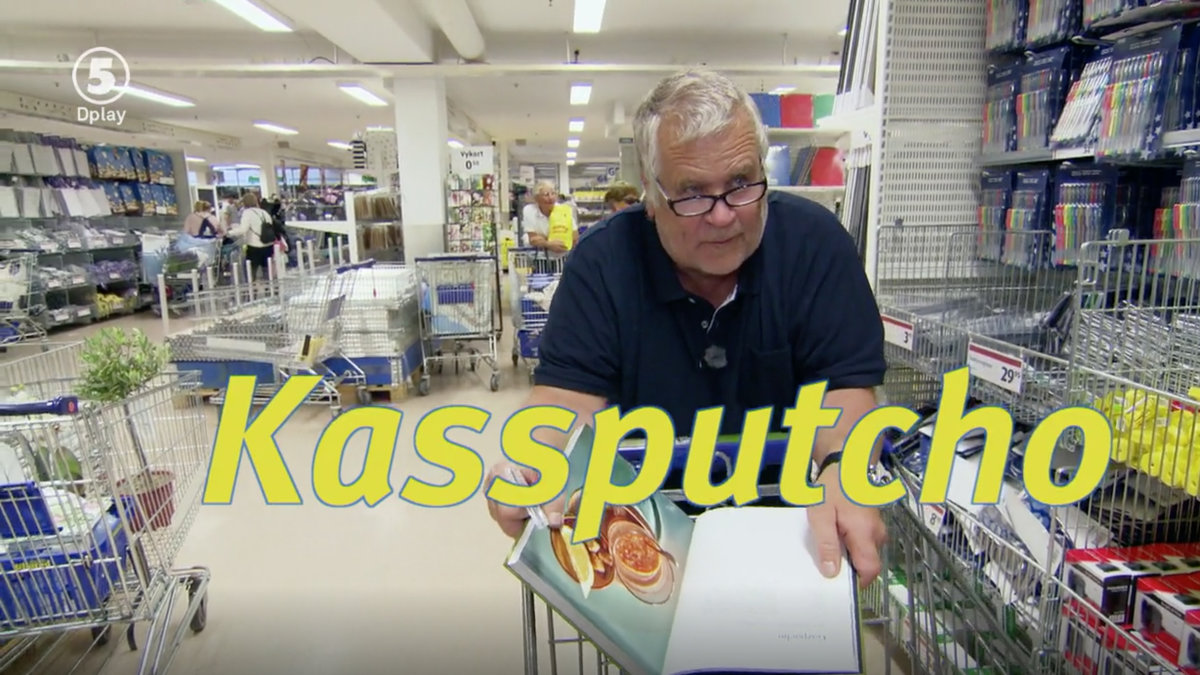 en äldre man i grått hår håller i en kokbok och i en kundvagn. 
