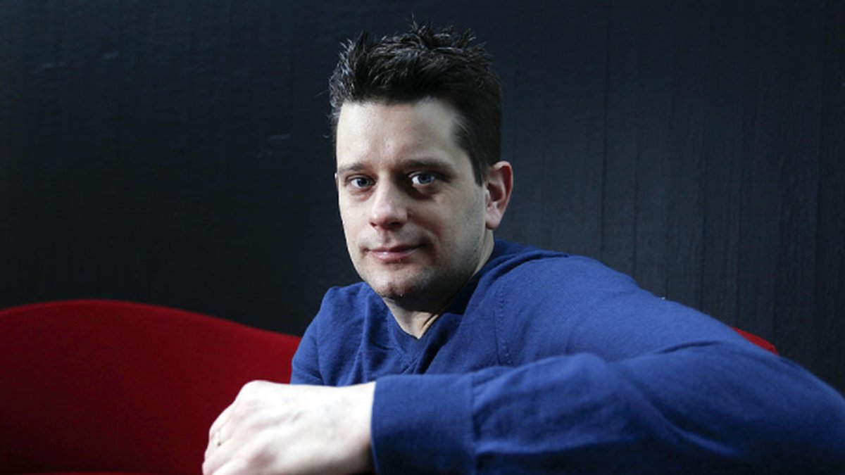 Marcus Birro sitter i en röd soffa