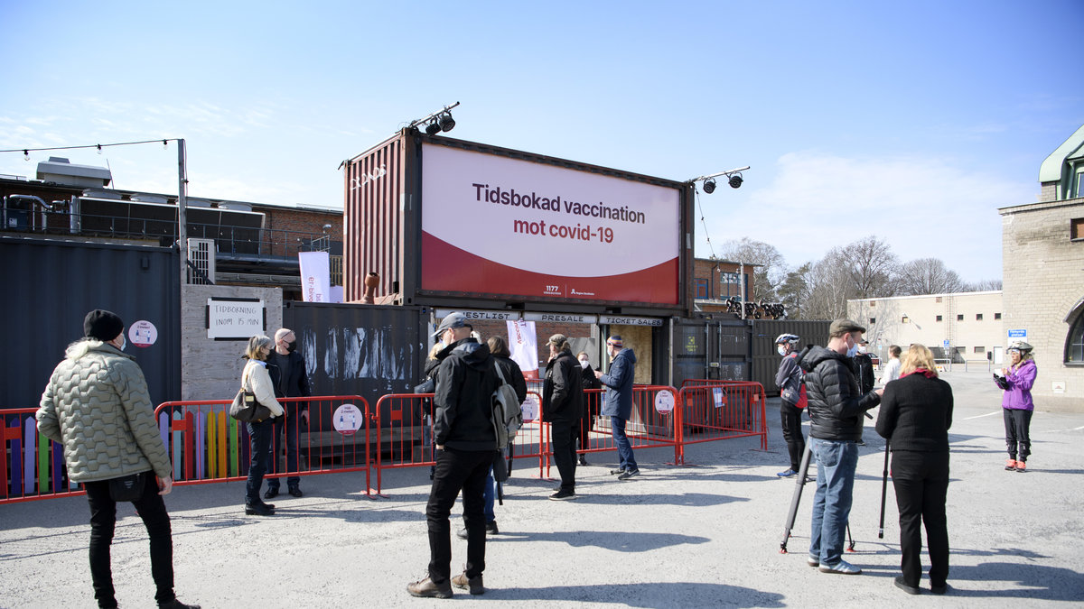 Människor väntar i kö inför vaccinering i klubblokalen Fållan i Stockholm.