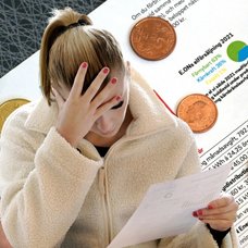 Kvinna läser av sin elräkning och i bakgrunden syns el hög elräkning.