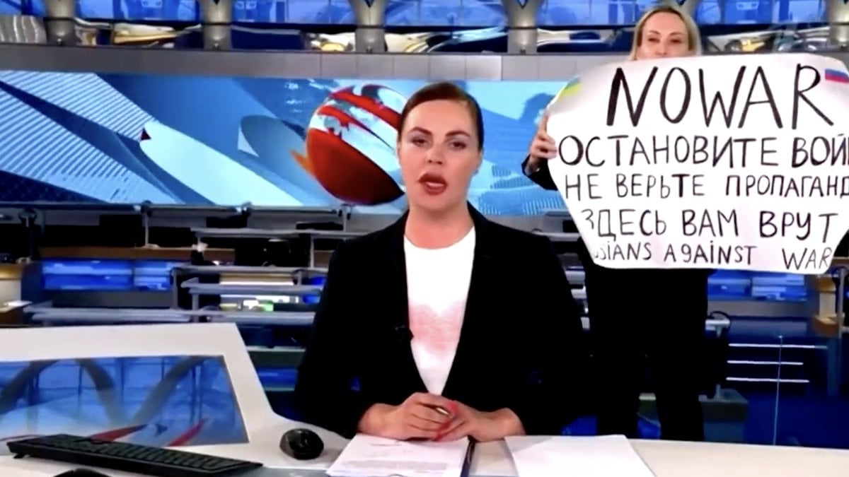 Kvinnan stormade in i nyhetssändningen med ett plakat.