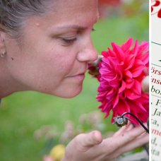 Kvinna doftar på en blomma i trädgården under sommaren och en almanacka.