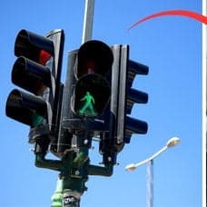 Trafikljus till vänster. Händer på en bilratt till höger. En röd pil pekar från trafikljuset till händerna på bilratten.