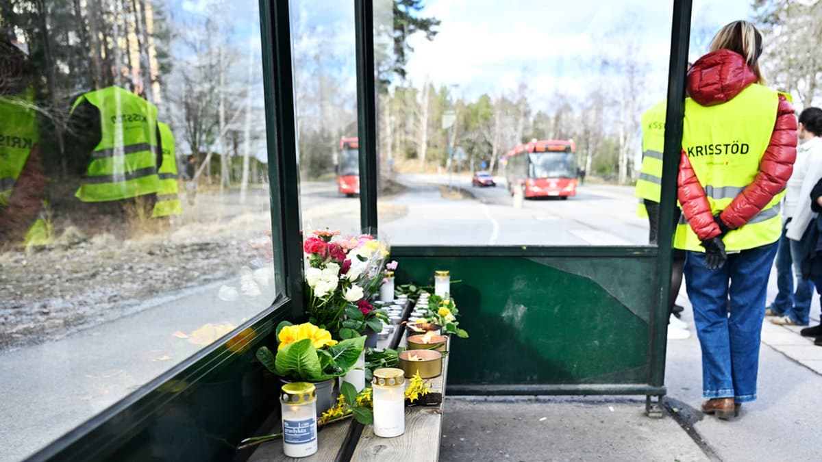 Blommor och ljus på sittbänken på busskuren i Tyresö där en skjutning skedde under 2026.