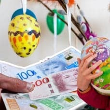 Påskpynt, pengar och ett barn med två påskägg.