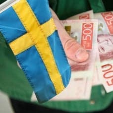 Svenska flaggan och en person som. håller i flera femhundralappar.