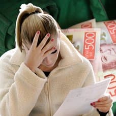 En kvinna med handen över pannan och i bakgrunden syns flera femhundralappar.