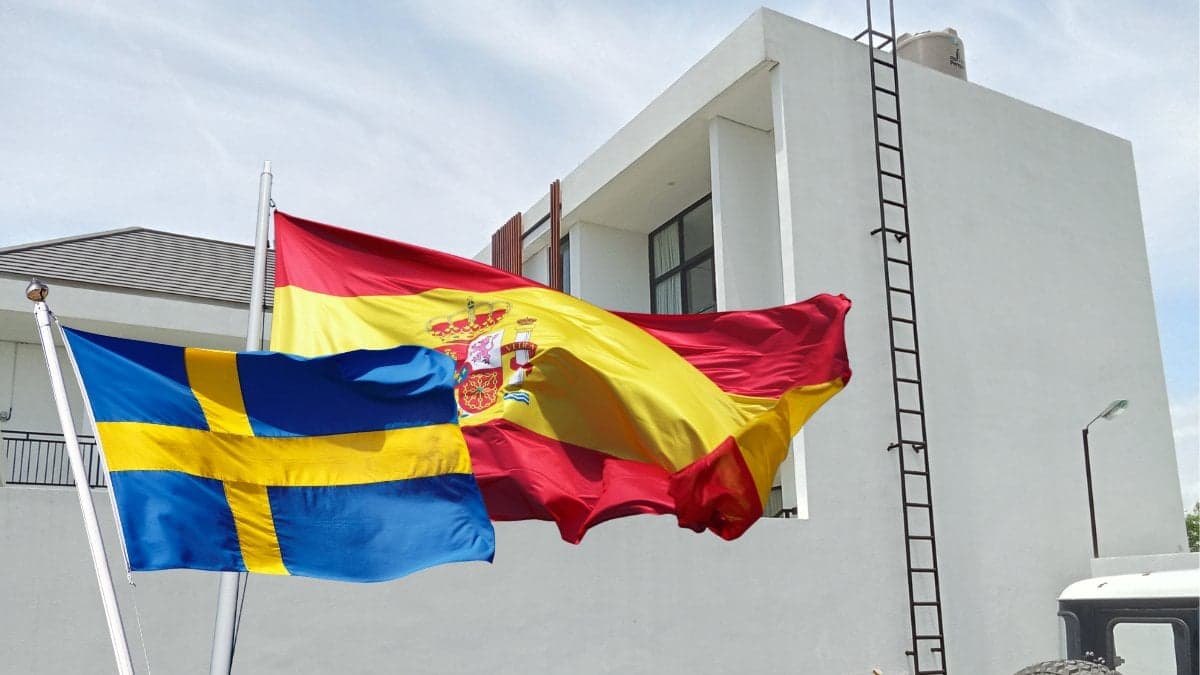 Hus i bakgrunden och Spanien-flagga samt Sverige-flagga utklippt vänster.