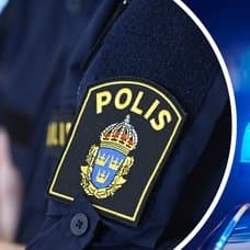 Polisemblem på en arm vänster. Blåljus höger.