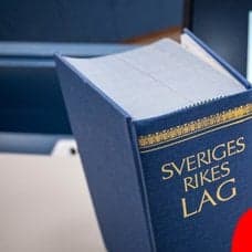 Lagbok i bakgrunde. Röd siluett av en man höger.