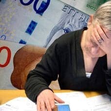 I bakgrunden syns pengar och sedan i förgrunden sitter en kvinna vid ett bord med ansiktet begravt i handen.