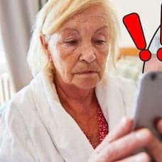Kvinna med mobiltelefon i handen och en tom plånbok med räkningar i bakgrunden.