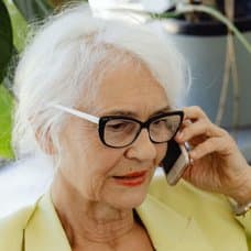 Äldre kvinna som pratar i mobiltelefon och en mobiltelefon med numret 070-1740635 inslaget