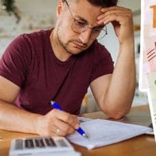 Ung man med dokument framför sig, svenska sedlar och deklaration i Skatteverkets app