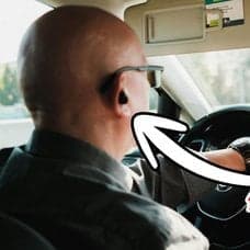 Man som kör bil med hörlurar och Europa-karta