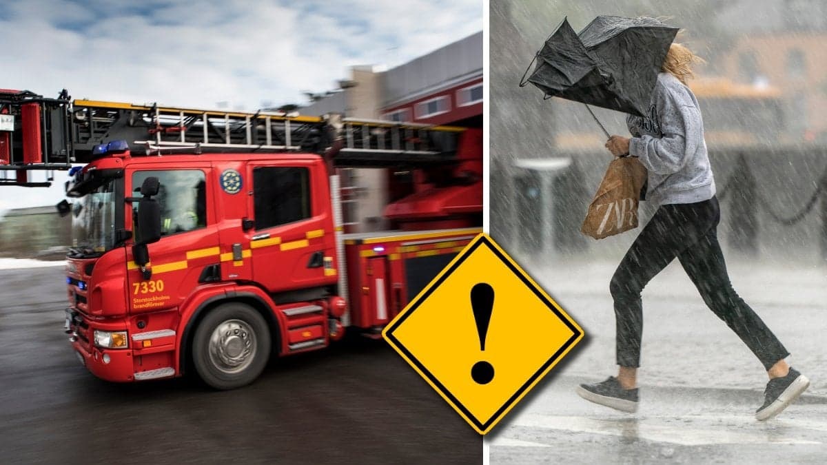 En brandbil på väg ut från garaget och en person i spöregn med uppfällt paraply.