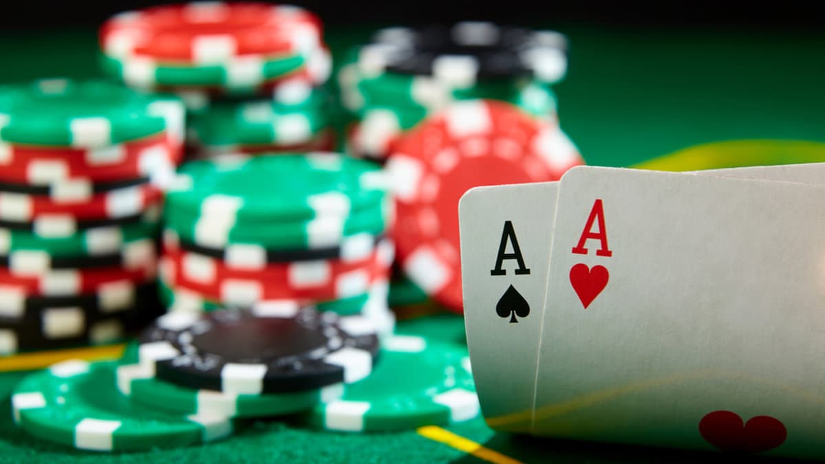 Massvis av marker på ett grönt pokerbord och två äss. 
