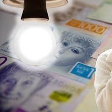 Pengar, glödlampa och kvinna med en faktura i handen.