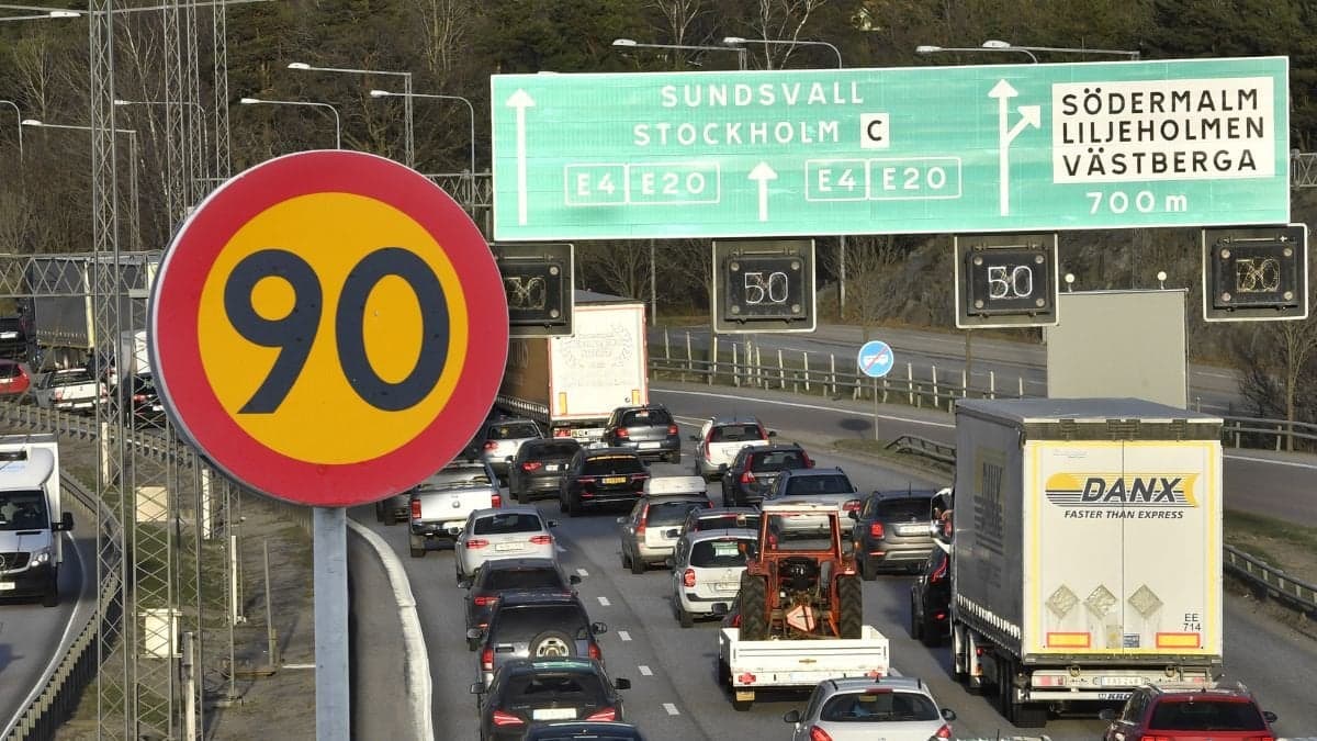 Hastighetsskylt och en motorväg med lastbilar och bilar.