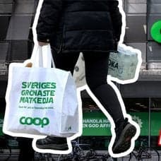Kvinna som går med Coop-påse och Coops logga på fasad