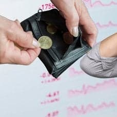 Plånbok, uppgiven man och fallande börskurser i bakgrunden.