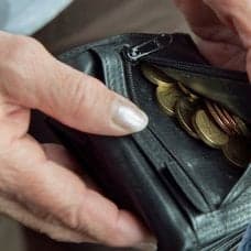 En plånbok med mynt i och en äldre kvinna.