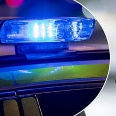 Bild på en polisbil med blåljus och en kvinna som pratar i telefon.