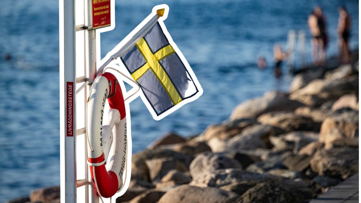 Svensk flagga och livboj vid vattnet.