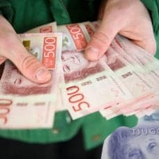 Pengar i handen, sedlar i bakgrunden och EU:s flagga.