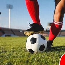 Ben som sparkar på en fotboll i bakgrunden. en röd siluett av en man till höger.