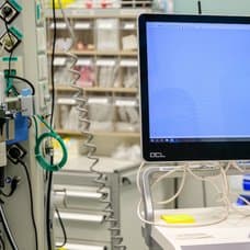 En kvinna som är sjuksköterska tittar på en dator i en vårdcentral.