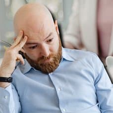 En person som lägger mynt i en spargris i bakgrunden. En utklippt bild på en stressad man till vänster.