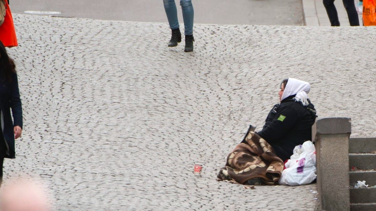 En tiggare sitter på en gågata