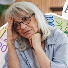 Äldre kvinna med bekymrad min, svenska sedlar och Kronofogden-skylt