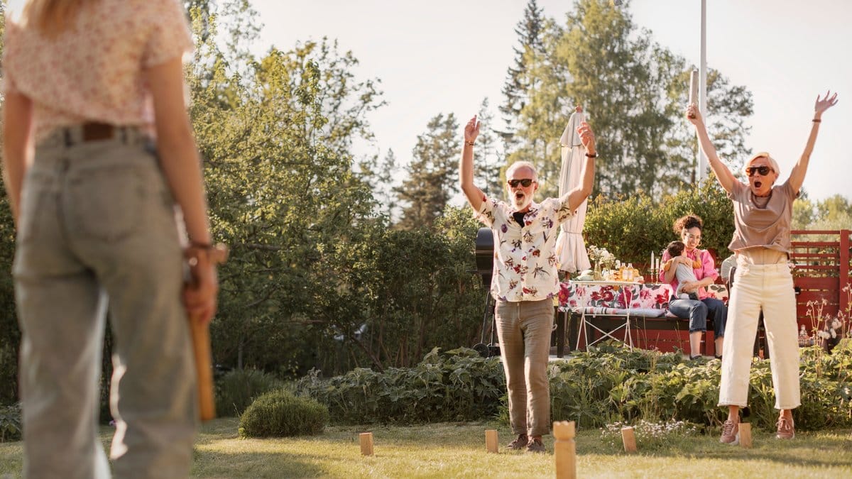 Människor spelar kubb ute i trädgården en sommardag