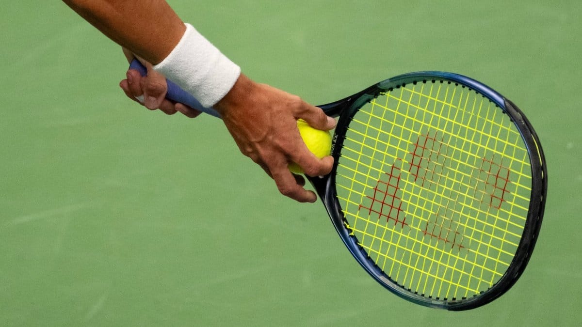 Bilden visar en arm som håller i ett tennisrack.