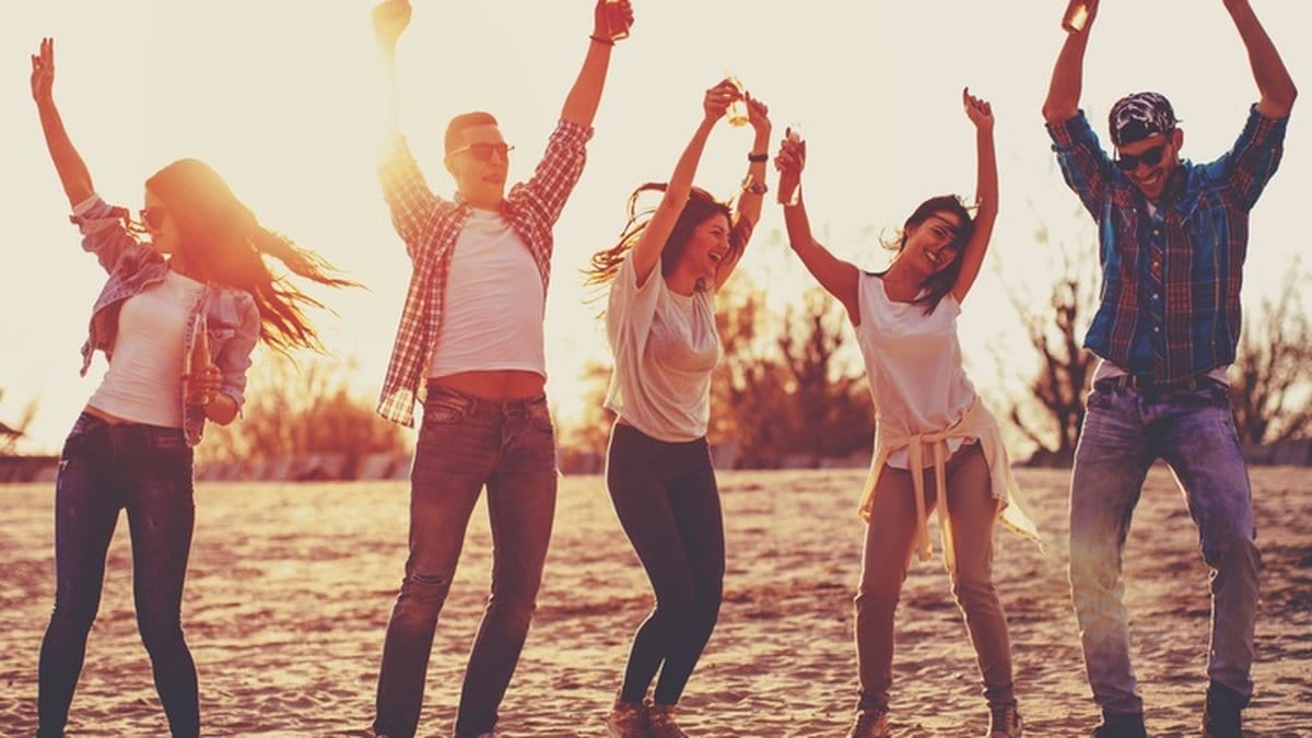 Fem personer hoppar i sanden