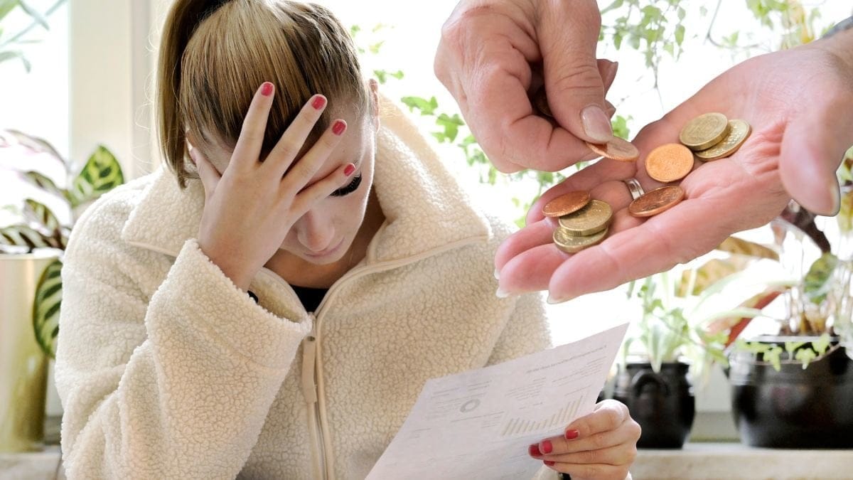 Kvinna med handen i pannan och mynt i handen.