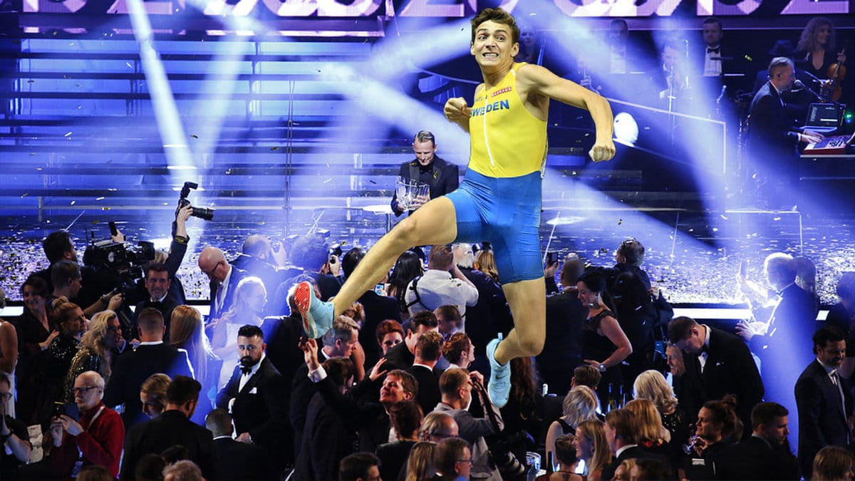 en man i blågul dräkt hoppar och slår med armen, en scen och publik