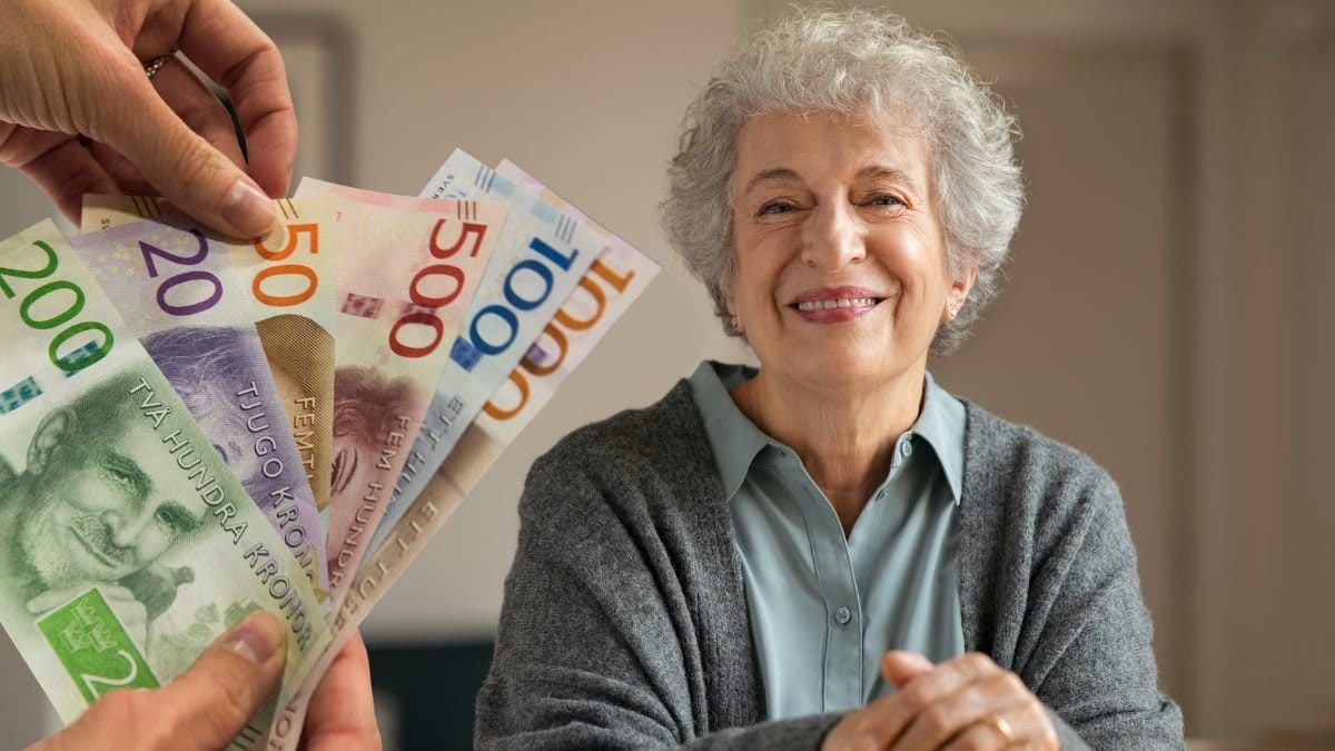 Sedlar i olika valörer i händerna och en glad kvinna med käpp.