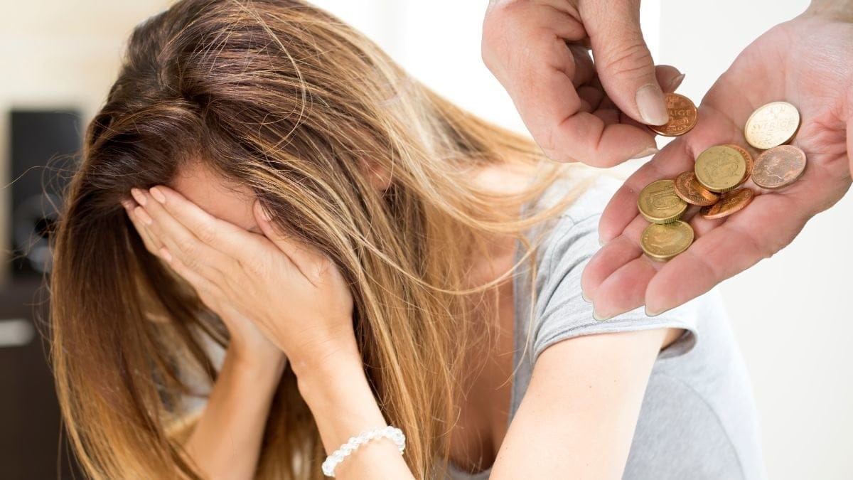 Ledsen kvinna och mynt i en hand.